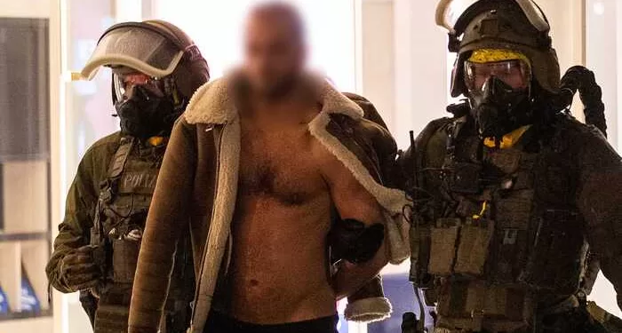A man (C) is lead away following his arrest by a Special Task Force (SEK) police officers wearing protective gear in Castrop-Rauxel, western Germany on January 8, 2023 on suspicion of preparing an 'Islamist attack' using cyanide and ricin. - Munster police and the Dusseldorf prosecutors' office said in a press release that officers searched a residence in the town of Castrop-Rauxel for 'toxic substances' intended to carry out an attack. (Photo by WTVnews / DPA / AFP) / Germany OUT