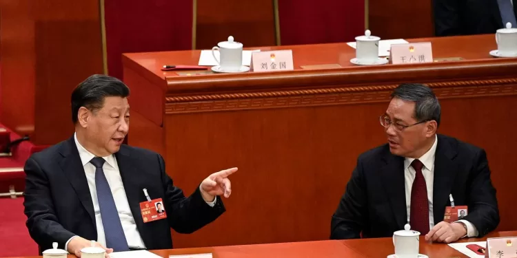 China's President Xi Jinping (L) speaks with Politburo Standing Committee member Li Qiang (R) during the fourth plenary session of the National People's Congress (NPC) at the Great Hall of the People in Beijing on March 11, 2023. (Photo by GREG BAKER / POOL / AFP)