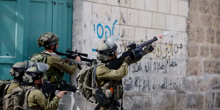 An Israeli soldier uses a weapon amid clashes with Palestinian protesters, in Hebron, in the Israeli- occupied West Bank April 1, 2022. REUTERS/Mussa Qawasma