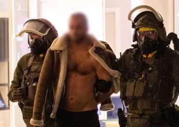 A man (C) is lead away following his arrest by a Special Task Force (SEK) police officers wearing protective gear in Castrop-Rauxel, western Germany on January 8, 2023 on suspicion of preparing an 'Islamist attack' using cyanide and ricin. - Munster police and the Dusseldorf prosecutors' office said in a press release that officers searched a residence in the town of Castrop-Rauxel for 'toxic substances' intended to carry out an attack. (Photo by WTVnews / DPA / AFP) / Germany OUT