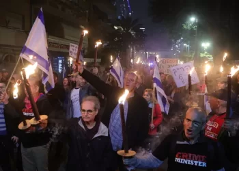 epa10394632 Israeli protesters light torches as they take part in a protest march against the new government in Tel Aviv, Israel, 07 January 2023. A statement made by the new minister of justice Yariv Levin declaring his intention to reform and weaken the power of the Israeli Supreme Court led people out to demonstrate against the new Netanyahu government  EPA/ABIR SULTAN