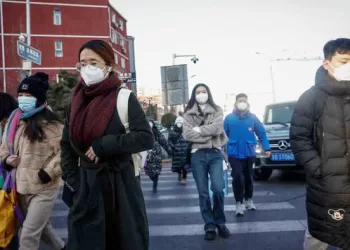 epa10386829 People wearing face masks walk in the business district of Beijing, China, 03 January 2023. Scientists have warned China that the country will face multiple waves of COVID-19 infections as the Omicron variant mutates to spread faster and evade immunity. According to virologist Shan-Lu Liu from Ohio State University in the USA, reinfection rates would rise as vaccine protection dwindled. People from Beijing, Shanghai and Wuhan have returned to work as restrictions have been lifted and as China attempts to recover its economy.  EPA/MARK R. CRISTINO