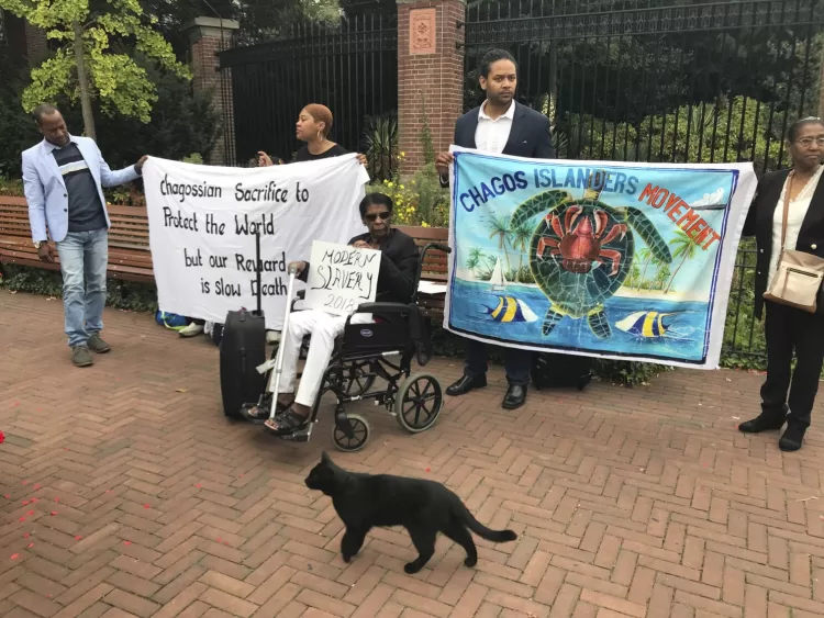 FILE - Protesters hold banners outside the World Court in The Hague, Netherlands, on Sept. 3, 2018, where judges listen to arguments in a case on whether Britain illegally maintains sovereignty over the Chagos Islands. Britain and the United States committed crimes against humanity when they forced the people of the Chagos Islands to leave their homes five decades ago to make way for a U.S. Navy base, a human rights group said Wednesday Feb. 15, 2023 as it called on the two governments to allow the Chagossians to return. (AP Photo/Mike Corder, File)