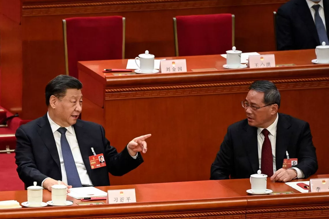 China's President Xi Jinping (L) speaks with Politburo Standing Committee member Li Qiang (R) during the fourth plenary session of the National People's Congress (NPC) at the Great Hall of the People in Beijing on March 11, 2023. (Photo by GREG BAKER / POOL / AFP)