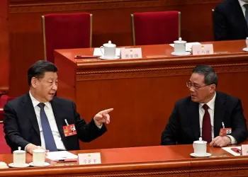 China's President Xi Jinping (L) speaks with Politburo Standing Committee member Li Qiang (R) during the fourth plenary session of the National People's Congress (NPC) at the Great Hall of the People in Beijing on March 11, 2023. (Photo by GREG BAKER / POOL / AFP)