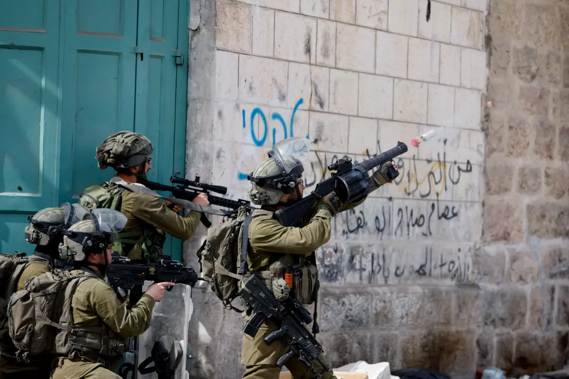 An Israeli soldier uses a weapon amid clashes with Palestinian protesters, in Hebron, in the Israeli- occupied West Bank April 1, 2022. REUTERS/Mussa Qawasma