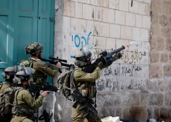 An Israeli soldier uses a weapon amid clashes with Palestinian protesters, in Hebron, in the Israeli- occupied West Bank April 1, 2022. REUTERS/Mussa Qawasma