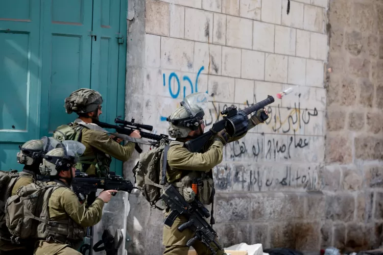 An Israeli soldier uses a weapon amid clashes with Palestinian protesters, in Hebron, in the Israeli- occupied West Bank April 1, 2022. REUTERS/Mussa Qawasma
