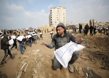 Palestinians carry bags of flour they grabbed from an aid truck near an Israeli checkpoint, as Gaza residents face crisis levels of hunger, amid the ongoing conflict between Israel and Hamas, in Gaza City, February 19, 2024. REUTERS/Kosay Al Nemer     TPX IMAGES OF THE DAY